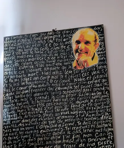 Un tableau noir couvert d’un long texte écrit à la main, avec son portrait