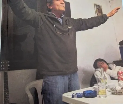 Les bras ouverts, devant une table