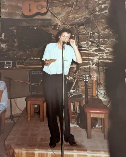 Seul au micro dans un cabaret aux murs de pierre