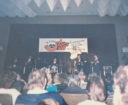 Un concert devant une salle pleine, sous une banderole de radio