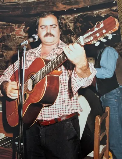 Un chanteur moustachu à la guitare, au micro